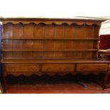 A 19th century oak dresser, with a plate rack, three short drawers, a wavy apron on turned legs