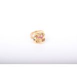 A Continental yellow metal and small ruby three stone leaf and entwined scroll ring, the flat