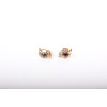 A pair of 9ct white and yellow gold and small sapphire and diamond three stone scroll stud earrings,