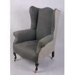 A George III style wing armchair with brass castors 85cm wide