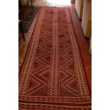 A red ground flatweave runner with geometric design 360cm x 100cm and a Middle Eastern type rug