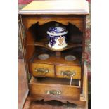 An oak tobacco cabinet with bevelled glass door, opening to reveal ceramic tobacco pot with two