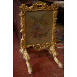 A Victorian carved gilt decorated firescreen inset with floral needlework