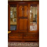 A Victorian walnut mirror door triple wardrobe with drawers below bearing retail label to the