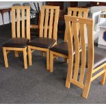 A set of four oak dining chairs with swept-down backs and dark brown seats.