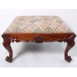 A Victorian large carved upholstered footstool with lion claw feet. h:42cm w:78cm d:78cm