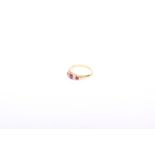 An 18k gold three stone ruby and diamond ring. central oval cut ruby flanked by 4 old cut diamonds