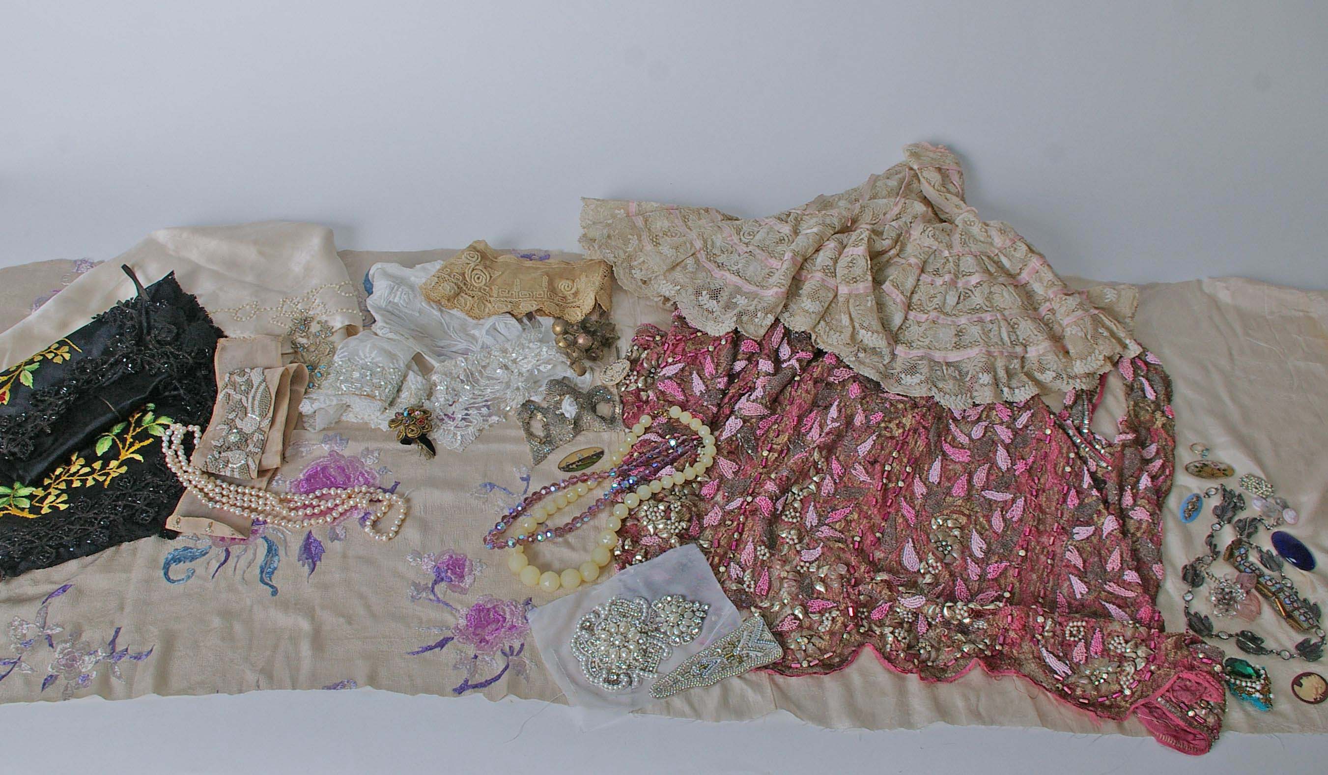 Part of a 1920s pink silk beaded garment, embroidered and beaded trimmings, a small leather bag, a