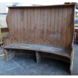 A late 19th/early 20th Century pine settle of curved outline 197cm high, 164cm wide