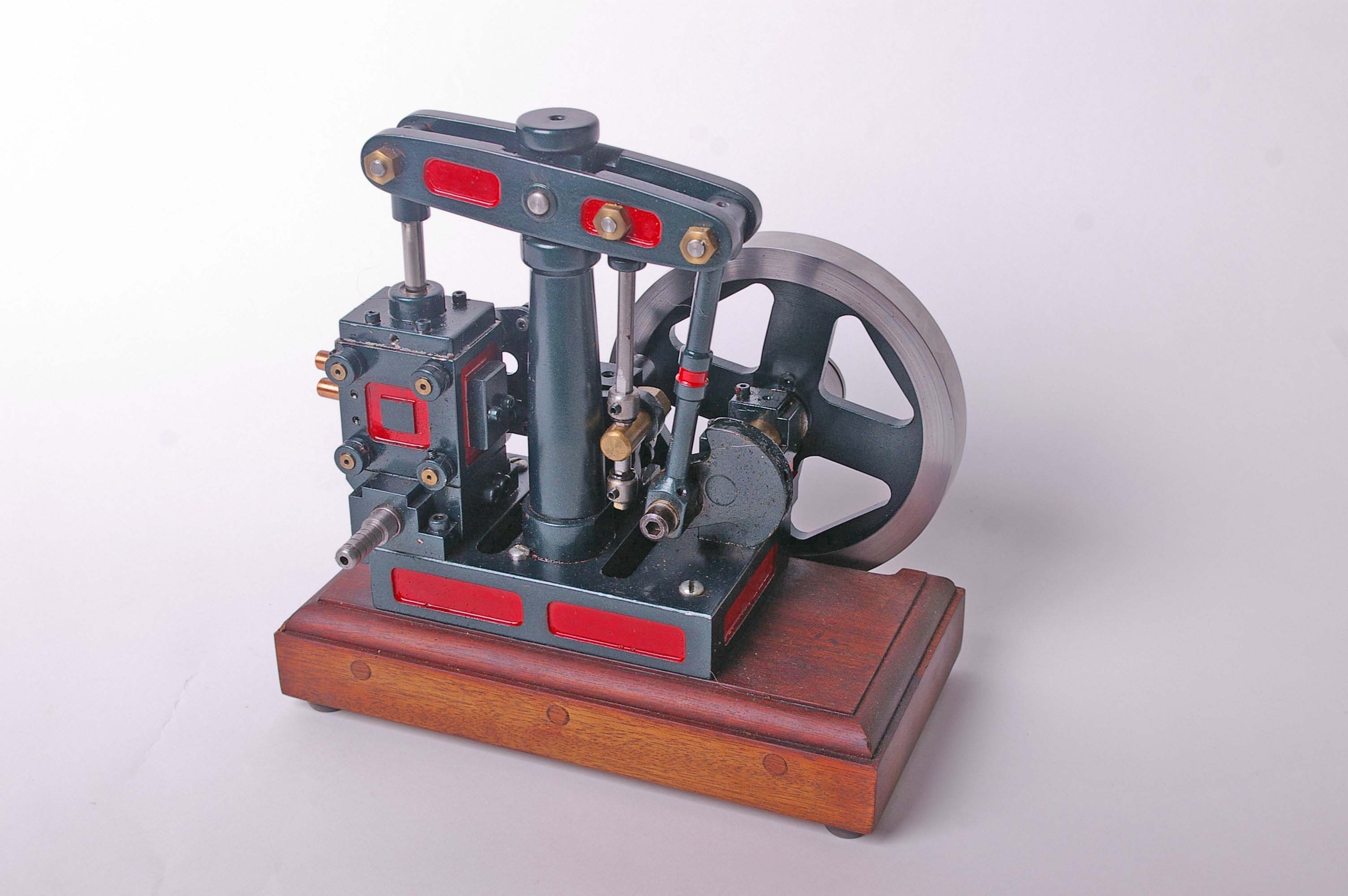 A model beam stationary engine in red and green livery on a mahogany plinth base. 25cm