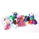 A collection of ribbons, comprising spotted satin ribbons, plain satin ribbons, spools of spotted