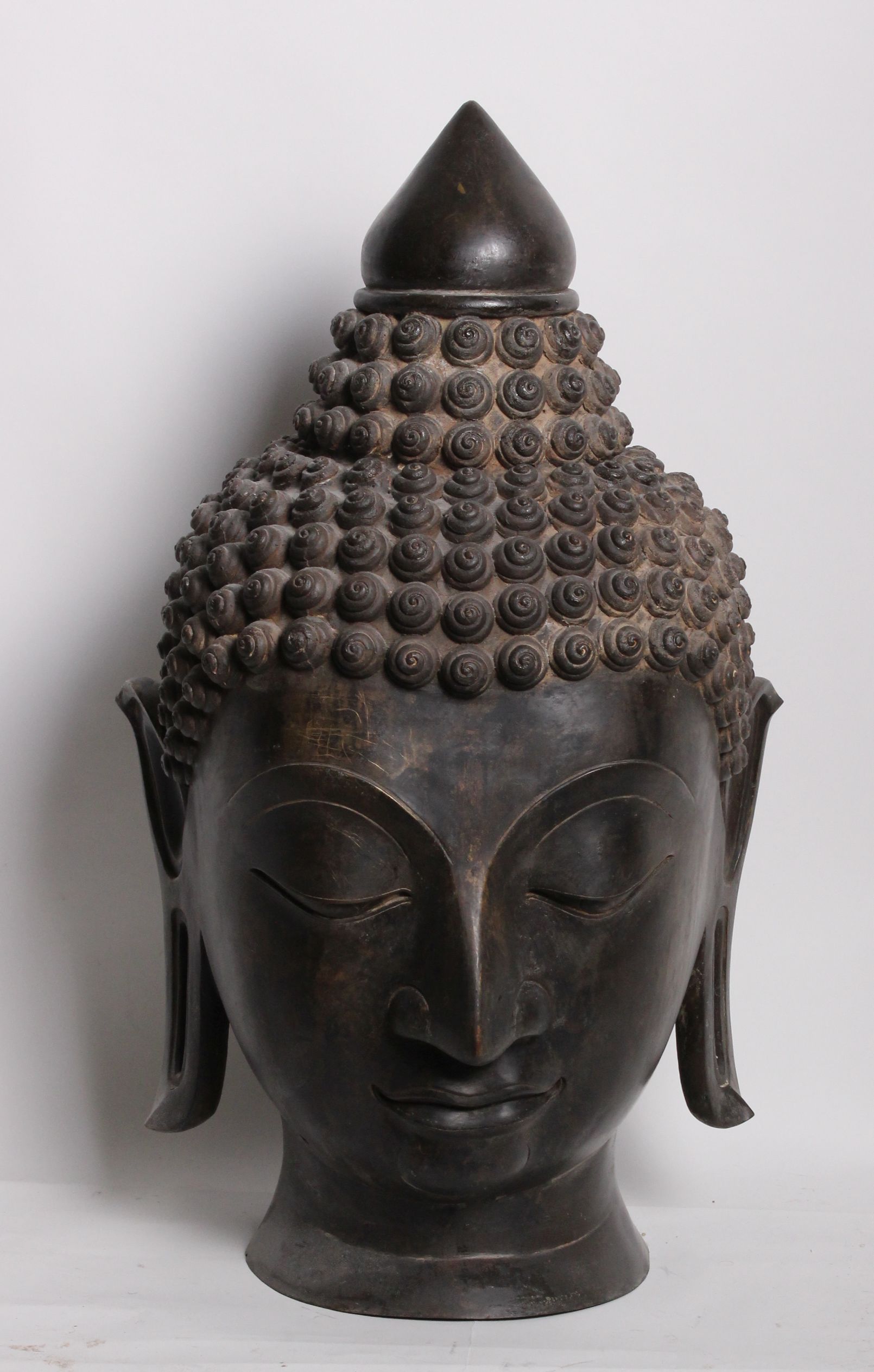 Two bronze heads of meditating Buddhas with elongated earlobes and tightly curled hair 80cm high