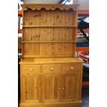 A modern pine dresser 205cm high, 123cm wide together with a cream chest of drawers with porcelain