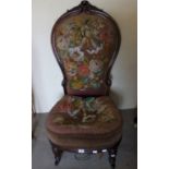 A Victorian walnut nursing chair with a carved frame and needlework upholstery