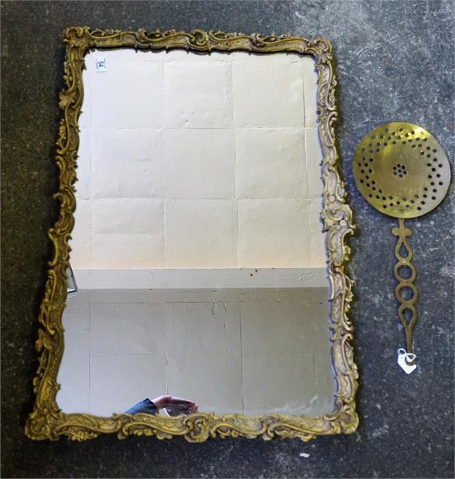 A guilt carved oblong wall mirror and a brass curd skimmer.