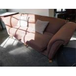 A 3 seater sofa with high sides, standing on turned mahogany feet, covered in a brown fabric.