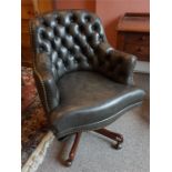 A reproduction deep buttoned backed leather desk chair on mahogany swivel base