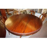 A large rosewood Victorian style round dining table standing on a four caved column base