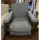 An Edwardian oak low easy chair with slatted arms and carved curved front