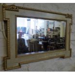 A gilt and painted framed oblong wall mirror, with carved decoration