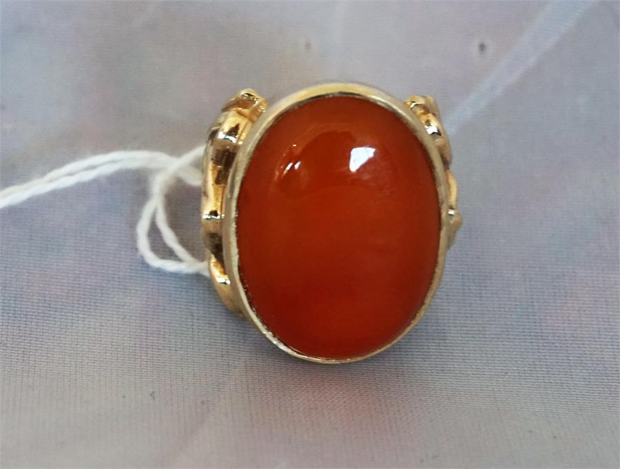 A Ladies gold dress ring set with a large Cornelian, the ring having pierced decorative sides.