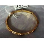 A gem set gold bangle, marks rubbed possible 18ct gold