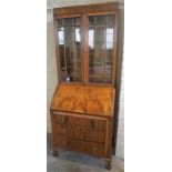 A Walnut Bureau Bookcase, with two glazed doors enclosing glass shelves above fall front and three