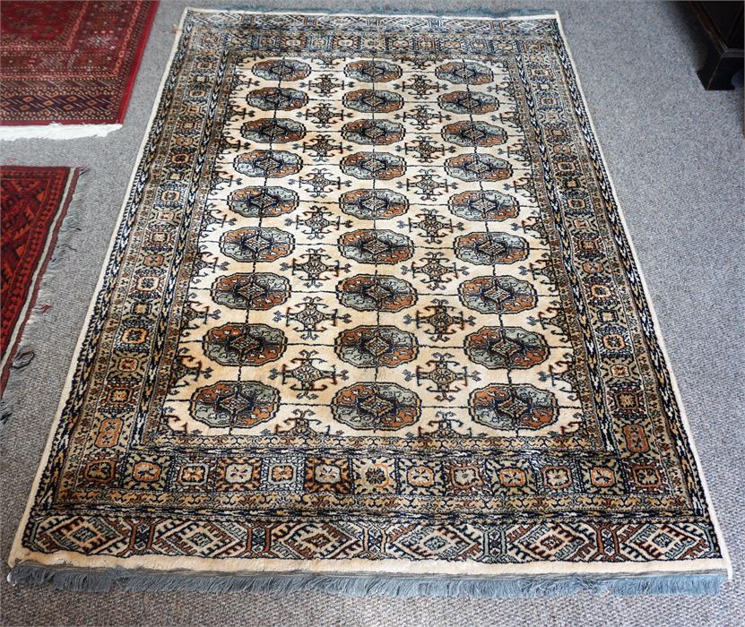 A Kashmir Machine Made Rug, Decorated with nine rows of three geometric panels, on a cream and beige