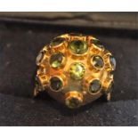 An 18ct Gold & Gemstone Dress Ring, with multiple small green gemstones, raised on a spherical