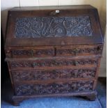 A Victorian Carved Oak Writing Bureau, with a fall front enclosing fitted drawers and pigeon