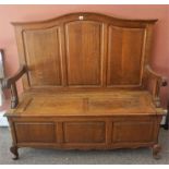 A French Oak Hall Bench/ Settle, with a panelled back rest above a hinged seat, raised on short