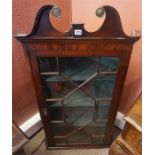 A George III Mahogany Hanging Corner Cabinet, with a broken swan pediment above a glazed astragal