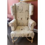 A Modern William & Mary Style Wing Armchair, Upholstered in a cream coloured golfing theme, 134cm