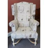 A Modern William & Mary Style Wing Armchair, Upholstered in a cream coloured golfing theme, 134cm