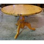 A Pine Kitchen Table, with a circular top, raised on a turned column and tripod legs, 77cm high,