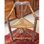 An Arts & Crafts Oak Corner Chair, With a woven rush seat, having a turned column frame with