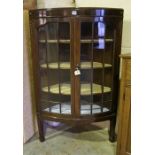 A Mahogany Corner Cabinet, with a glazed door enclosing a shelved interior, raised on tapered