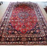 A Large Meshed Rug, Decorated with all over floral medallions and motifs on a red ground, 282 x