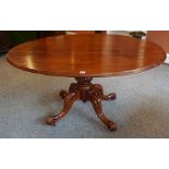 A Victorian Mahogany Snap Action Supper Table, the oval tilt top is raised on a turned column