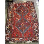 A Small Persian Rug, Decorated with geometric medallions and motifs on a red ground, 127 x 85cm
