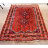 An Iranian Shiraz Rug, Decorated with two central geometric medallions on a red ground, 197 x 145cm