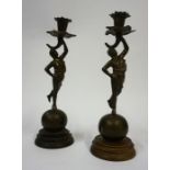 A Pair of Cast Bronze Figural Candlesticks, Modelled as a semi-clad nude, raised on a ball stand,
