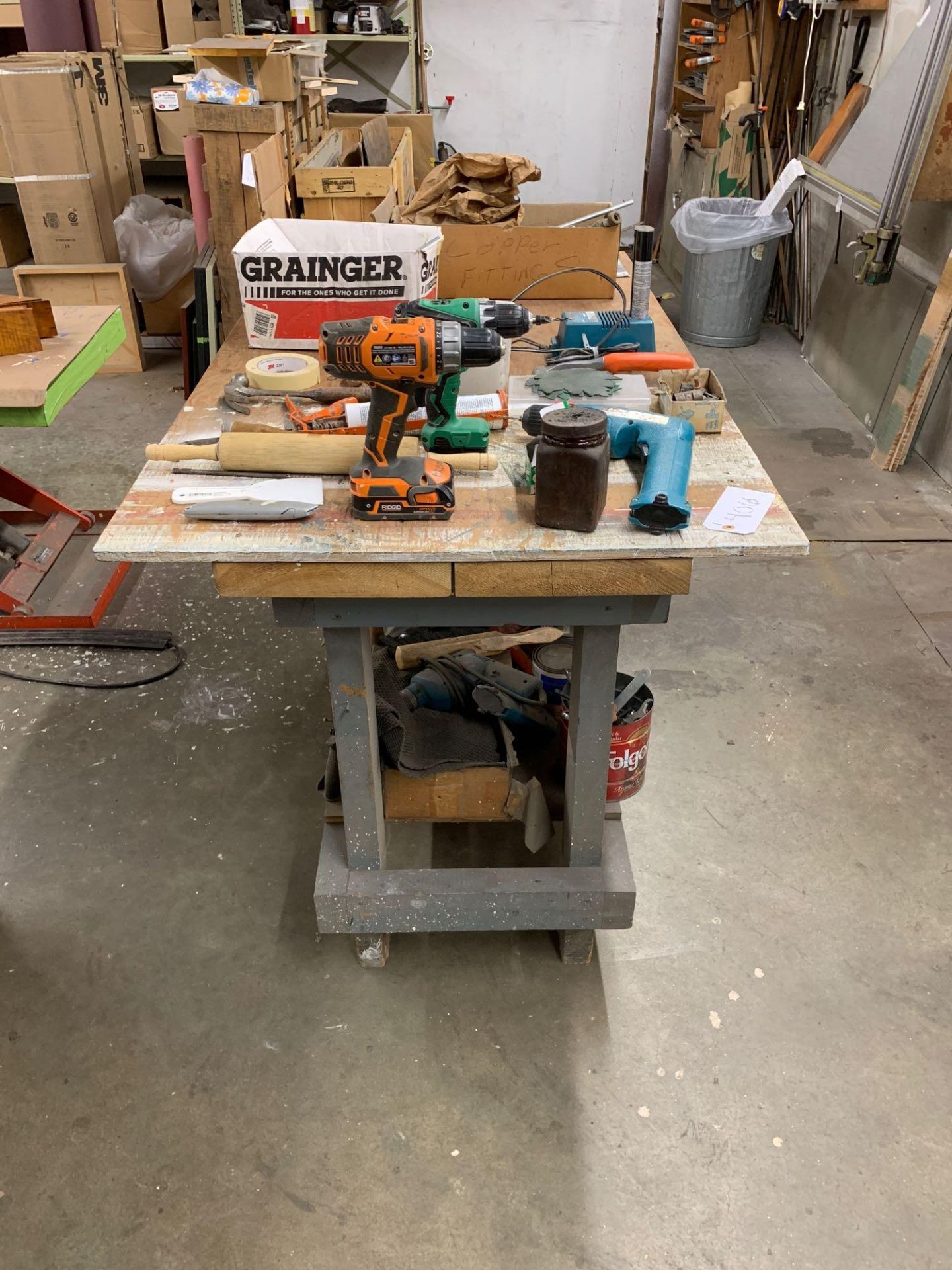 Work bench with misc parts and tools including Makita drills and batteries