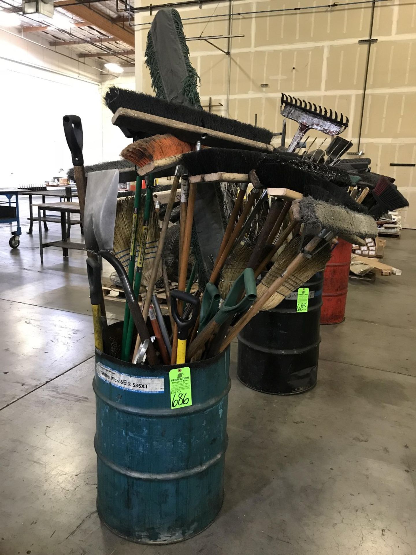 Drum of Assorted Push Brooms, Shovels, and Pitch Forks