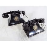 A pair of child's black bakelite battery operated telephones linked by twisted wire cord,