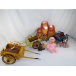 Three wooden carts containing a set of five miniature dolls,