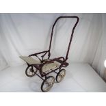 A vintage metal framed pushchair with leather seat and safety strap.