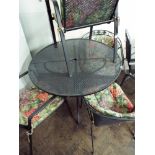 A circular metal garden table with two pairs of black metal chairs