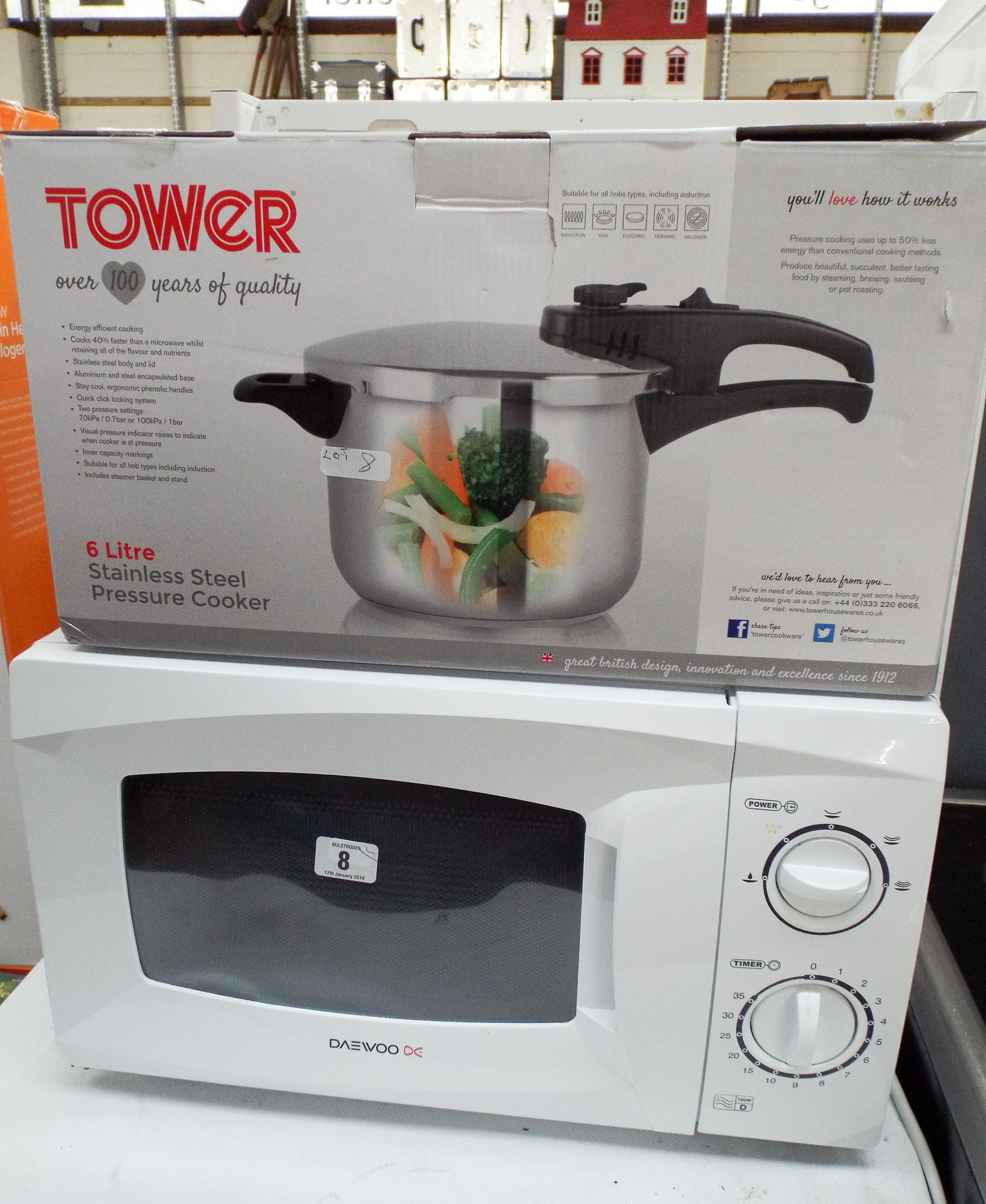A Daewoo microwave oven in a white case and a six litre stainless steel pressure cooker
