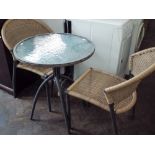 A circular glass top garden table with two rattan style chairs